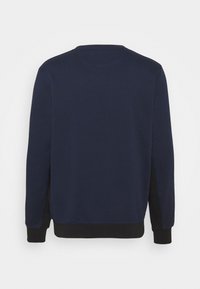Sweat-shirt bleu marine avec poignets et taille noirs, montré de dos sur un fond blanc uni.