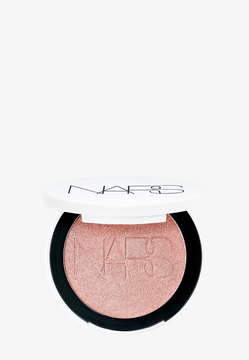 Compacta de iluminador NARS con un polvo embellecido en rosa dorado brillante. Caja redonda blanca con detalles negros y el logo de NARS en la tapa.