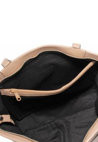 Beige leren handtas interieur met een gladde textuur, voorzien van een zwarte stofvoering en een ritsvak voor extra opbergruimte.