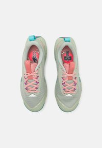 Zapatillas deportivas verde claro con una parte superior de malla texturizada, cordones rosas y morados, y una lengüeta en el talón turquesa; presenta un diseño único en la plantilla.