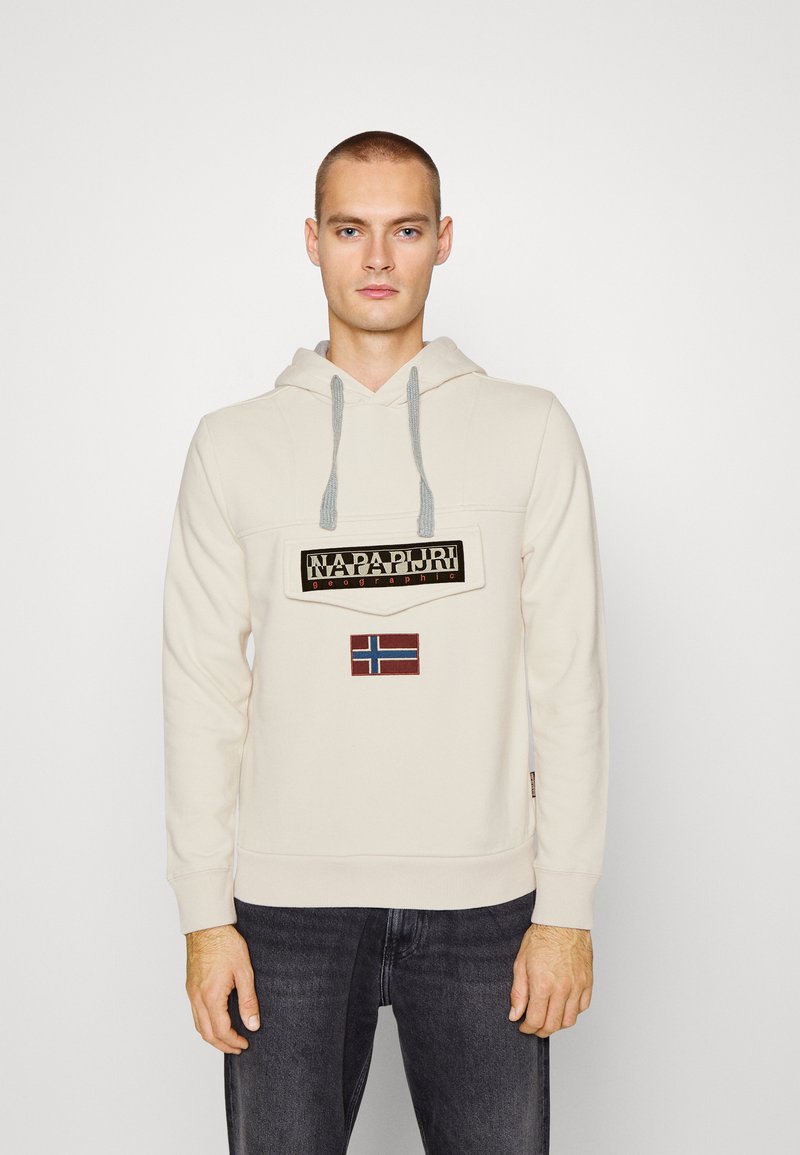 Felpa crema con coulisse grigia, caratterizzata da un'etichetta con logo nera e una piccola patch della bandiera norvegese sul davanti. Tessuto morbido, vestibilità standard.