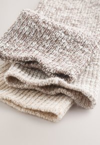 Ensemble de trois écharpes tricotées dans des tons crème et brun, présentant une texture côtelée et des bords pliés pour une finition douce et confortable.