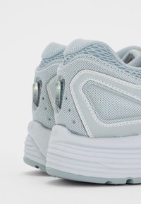 Light blue athletic shoes with a mesh upper, padded collar, and white rubber sole. Features textured accents and visible air cushioning.
