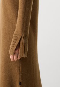 Vestito a maglia marrone con design affusolato, polsini a coste, spacchi laterali e una piccola etichetta ECOALF all'orlo. Tessuto morbido.
