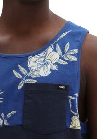Débardeur bleu à motif fleuri jaune, avec une poche marine et un petit logo Vans, fabriqué en tissu doux avec une finition texturée.