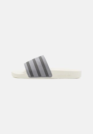 Hvid slidesandal med en grå rem med tre mørkegrå striber på en ensfarvet hvid baggrund.