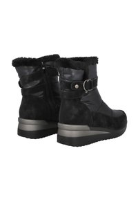 Par de botas de invierno negras con forro de piel, cremallera lateral, hebilla decorativa y suelas gruesas en gris y negro.