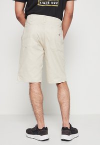 Shorts cargo beige con dos bolsillos traseros, diseñados para la utilidad. Hechos de tejido duradero, con un corte recto y costuras reforzadas.