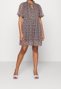 Vestido corto de flores con mangas cortas en tela oscura, con escote en forma de llave y cintura fruncida. Sandalias de tacón abierto de color púrpura claro con textura.