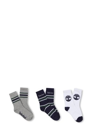 Trois paires de chaussettes : grises avec des rayures vertes, bleu marine avec des rayures blanches et vertes, et blanches avec un logo noir. Matériau en mélange de coton.
