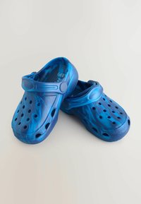 Blå plastträskor med en slät yta, utrustade med flera ventilationshål och ett justerbart rem för en säker passform.
