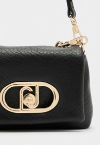 Borsa a tracolla in pelle nera con una superficie testurizzata, dotata di un logo ovale in tono oro prominente e di un attacco con chiusura in metallo dorato.