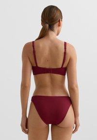 Bordowy komplet bikini wykonany z teksturowanej tkaniny, z regulowanymi ramiączkami i zapięciem z tyłu, pokazany od tyłu.
