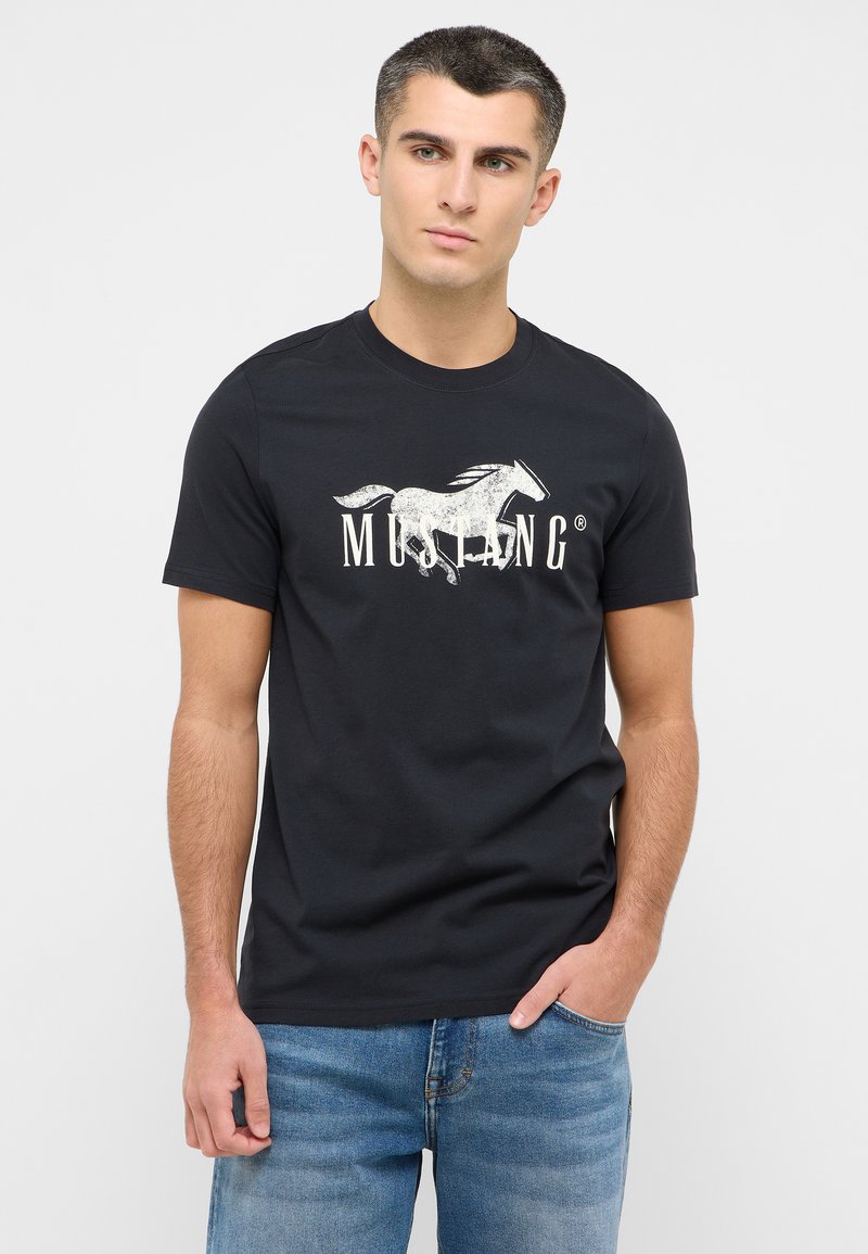 Černé bavlněné tričko s bílou grafikou bujného koně a výrazným nápisem "MUSTANG". Krátké rukávy, design s kulatým výstřihem.