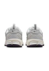 Baskets de sport grises et blanches avec une partie supérieure en mesh texturé, une semelle en caoutchouc contrastante et une languette à l'arrière ; logo Nike sur le talon.
