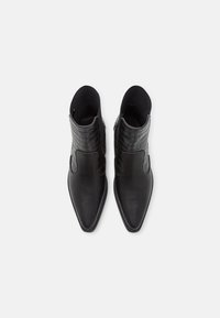 Botines negros hasta el tobillo con puntera afilada, confeccionados en cuero sintético liso y texturizado, con acentos de patrón de cocodrilo y lados elásticos.