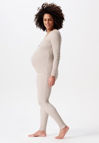 Zwangere loungewear set van zacht beige stof, met een longsleeve top met een ronde hals en aansluitende leggings met een geribbelde textuur.
