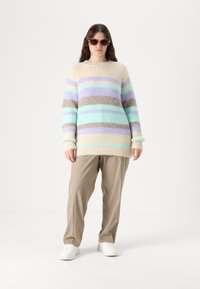 Daugiaspalvis dryžuotas megztinis, pasižymintis minkšta, pūkuota tekstūra pastelinėse žaliuosiuose, levandų, smėlio ir rudos spalvų atspalviuose. Derinamas su smėlio spalvos kelnėmis.