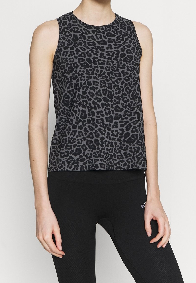 Czarny bezrękawnik w wzór lamparta, z okrągłym dekoltem i luźnym krojem, zestawiony z czarnymi legginsami o wysokim stanie.