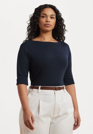Navy blue fitted top with 3/4 sleeves, round neckline, smooth texture. Paired with cream pleated trousers and a brown belt.