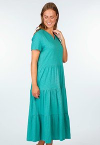 Türkises Maxikleid aus weichem Stoff, mit V-Ausschnitt, kurzen Ärmeln und gestuftem Design mit gerafften Akzenten.