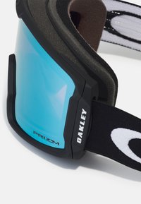 Zwarte skibril met een blauw reflecterend lenzen, een geveerd frame en een verstelbare band met witte logo-accenten. "Prizm" is op de lens gedrukt.