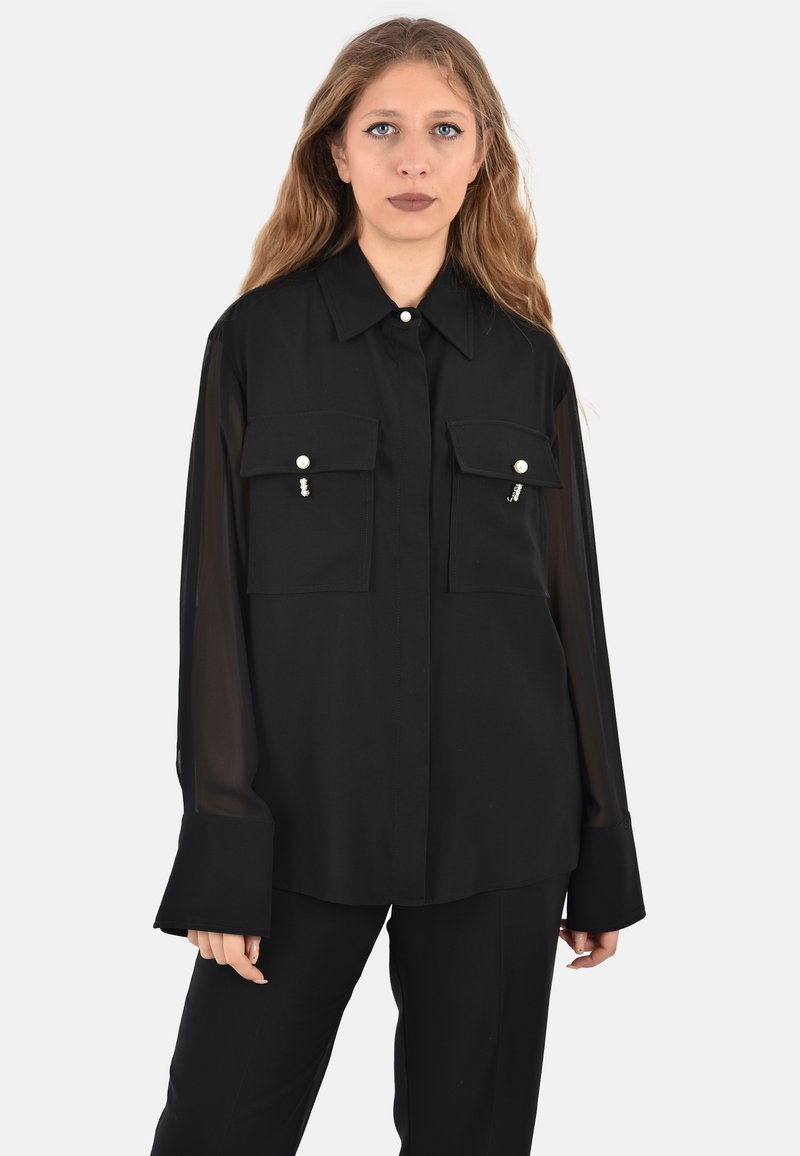 Camicia nera a maniche lunghe realizzata in tessuto leggero, con due tasche sul petto decorate con dettagli perlacei e colletto classico.