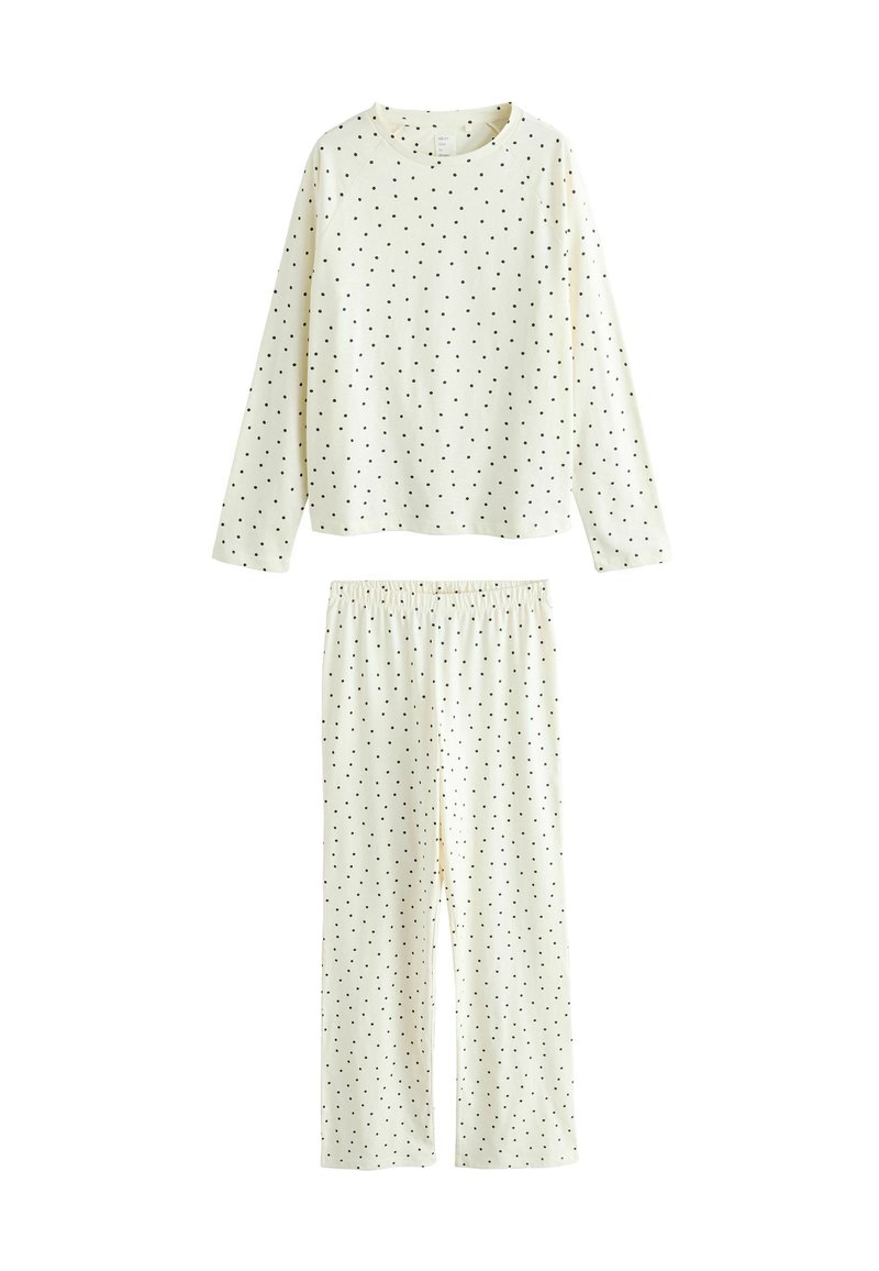 Lys beige pyjamasæt med langærmet top og bukser med elastisk talje, begge med sort polkaprikmønster. Blød stoftekstur.