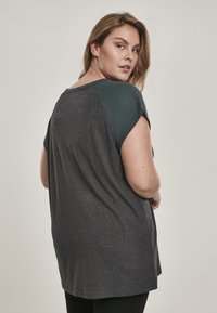 Korte mouw top met een donkergrijze stof en groene schouderpanelen, met een relaxed fit en een zachte, textuurstof.