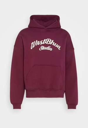 Haut à capuche bordeaux avec poche avant et texte en cursive blanche "WnstBhvr Studio" sur la poitrine, présenté sur un fond clair uniforme.