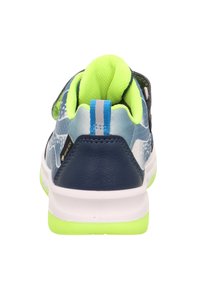 Zadní pohled na atletickou obuv s modrým svrškem, zelenými akcenty a texturovaným povrchem. Obsahuje pásek na suchý zip a bílou podrážku.
