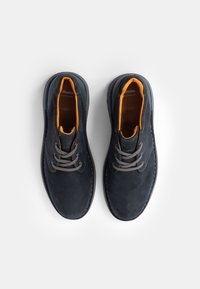 Pantofi din piele bleumarin închis cu sireturi gri, căptușeală portocalie și tălpi din cauciuc. Au o textură netedă și un design subtil.