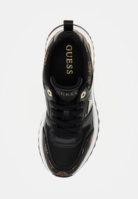 Sneaker nera con accenti oro, caratterizzata da una tomaia texturizzata, chiusura con lacci e una suola bianca chunky. Logo esposto sulla linguetta.