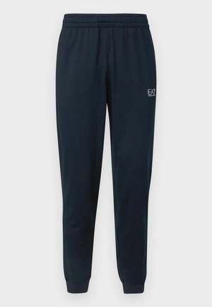 Pantalones deportivos azul marino ajustados con cinturilla elástica, puños en los tobillos y pequeño logo blanco EA7 Emporio Armani en el muslo derecho.