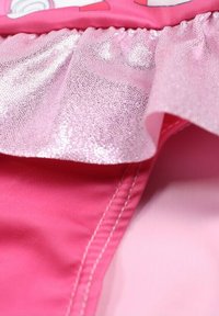 Tissu rose présentant un vol de ruffles brillant et texturé. Section inférieure lisse avec un éclat subtil. Coutures contrastantes visibles le long de la couture.