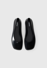 Scarpe flat nere realizzate in materiale lucido, con punta arrotondata, design minimalista e una morbida fodera interna per il massimo comfort.