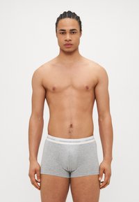 Boxers gris avec une taille blanche étiquetée "COPENHAGEN STUDIOS." Tissu lisse, design ajusté et longueur mi-cuisse.