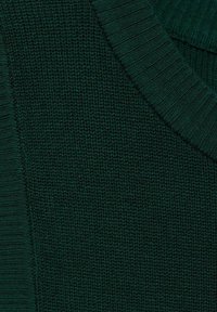 Tessuto lavorato a maglia di un verde scuro con bordi a costine e un motivo testurizzato, che mostra una sezione piegata del materiale.