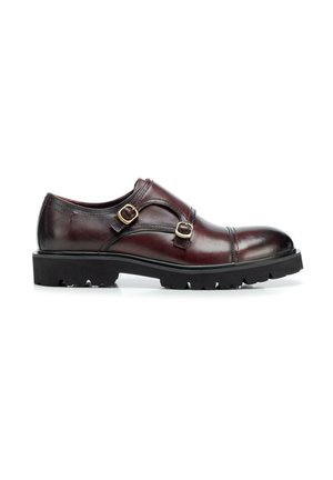 Ciemnobrązowy skórzany but typu monk strap z podwójnymi złotymi klamrami i czarną, wytrzymałą podeszwą, widziany z boku.