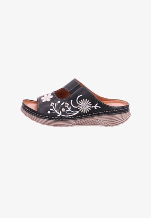 Black slip-on sandal with beige floral embroidery, thick textured sole, and cushioned interior.