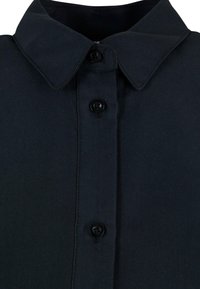 Chemise noire à boutons avec un col pointu, arborant des boutons de la même couleur, fabriquée dans un tissu lisse et texturé.