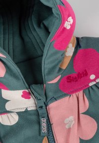 Felpa con motivo floreale in teal, rosa e crema. Presenta un colletto alto e una zip; logo ricamato sul colletto e tessuto testurizzato.