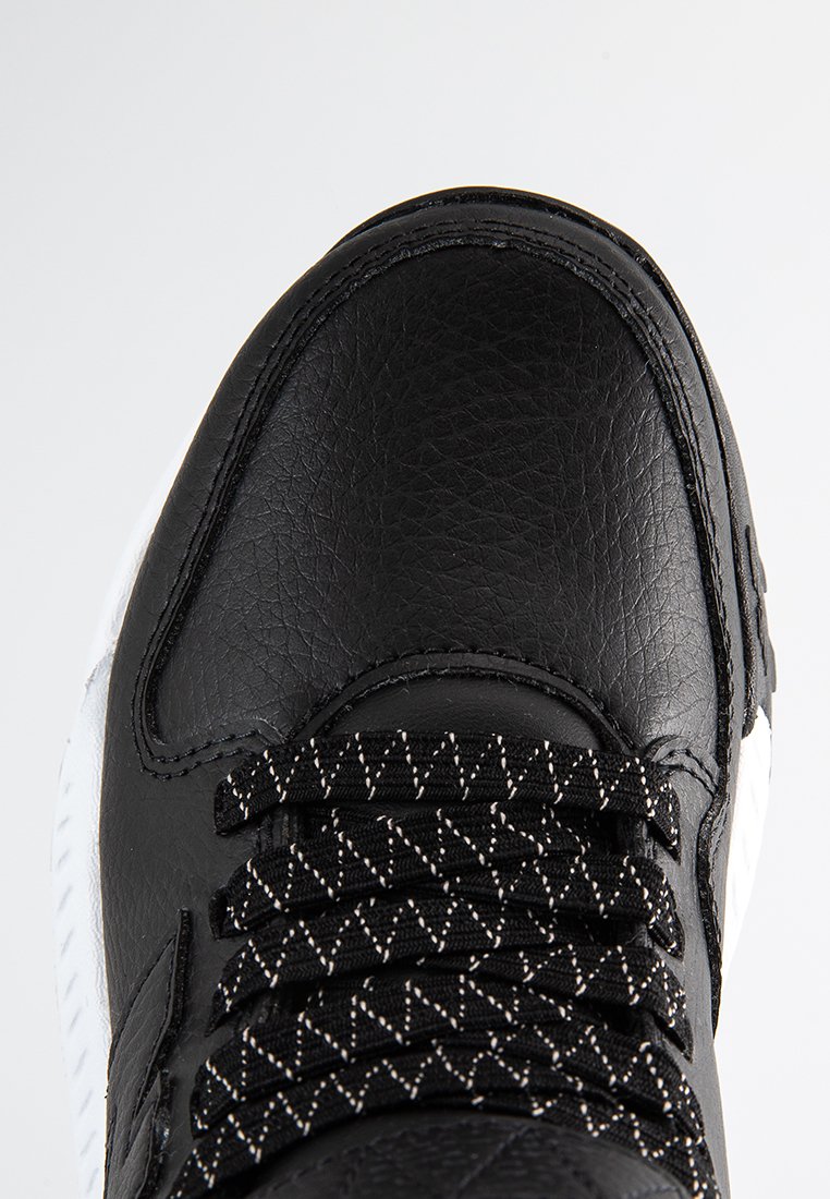 Baskets en cuir noir avec-dessus texturé, semelle blanche et lacets noirs avec un motif en losange. Fini lisse et protège-orteils renforcé.