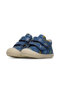 Des chaussures bleues à motif dinosaure avec deux bandes Velcro, des semelles en caoutchouc, et un capuchon orteil texturé de couleur crème. Fabriquées en matériau synthétique.