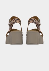 Paire de sandales compensées avec semelles épaisses beige et brides de cheville imprimé léopard avec boucles argentées, vues de dos.