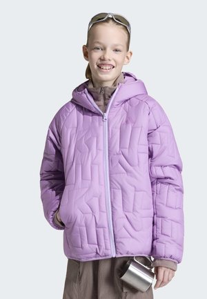 Junge Person lächelt, trägt eine lilafarbene gesteppte Jacke und Sonnenbrille auf dem Kopf, hält einen Campingbecher aus Edelstahl in der Hand.