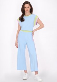 Kék, rövid ujjú overáll, zöld és rózsaszín díszcsíkokkal, rugalmas derékrésszel és széles lábakkal. Puha anyagból készült.