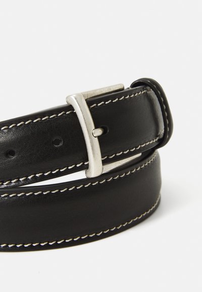 Ceinture en cuir noir avec des coutures blanches et une boucle en argent. La sangle est lisse avec un léger éclat, avec des trous pour l'ajustement.