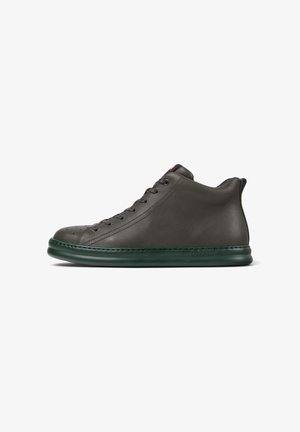 Hoge, donkergrijze sneaker met een gladde leren afwerking, voorzien van een groene rubberen zool en contrasterende veters, schuin gepositioneerd om het ontwerp te tonen.