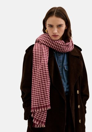 Gingham-patterned scarf in burgundy and pink hues, made of soft fabric, finished with fringed edges, worn around the neck.